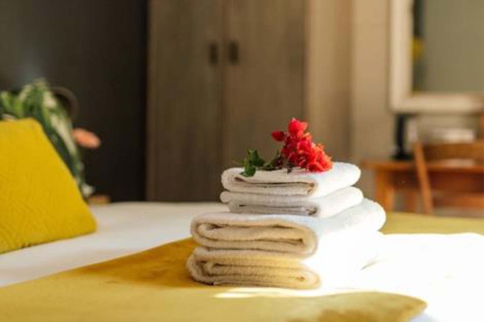 Folded towels with a red flower on a bed